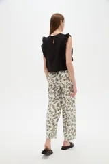 Pantalón de algodón estampado con diseño botánico de hojas en tonos verdes sobre base blanca, de corte holgado, tiro medio y cintura elástica con cordón de ajuste ajustable.