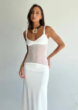 Vestido largo blanco con breteles finos y paneles de tela traslúcida en la zona del abdomen y la cadera.