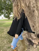 Sweater color beige de tejido de punto con cuello alto, mangas largas y corte asimétrico con volados en el ruedo.