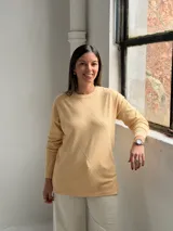 Sweater de punto color manteca con diseño de rombos en relieve, cuello redondo y mangas largas con puños ajustados.
