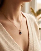 Collar de cadena fina en color dorado con un dije colgante en forma de gota con piedra negra de onix.