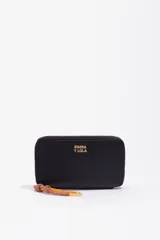 Billetera rígida de color negro con cierre de cremallera perimetral. Presenta el logo metálico de Bimba y Lola en color dorado en el frente y un tirador de cordón trenzado en tonos marrón y amarillo. El interior cuenta con compartimentos para tarjetas y un monedero con cierre.