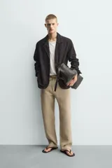 Blazer de corte relajado confeccionada en piel con acabado de ante. Presenta cuello con solapas de muesca, cierre frontal de dos botones, mangas largas y bolsillos de plastrón en la parte delantera. Destaca por sus costuras con efecto lavado que le otorgan un aspecto vintage.