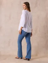 Blusa blanca de tejido labrado con cuello redondo, escote en V y aplique metálico.