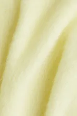 Buzo de punto suave color amarillo pálido, con textura afelpada, cuello redondo y mangas largas de corte amplio.