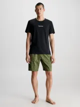 Conjunto de pijama Calvin Klein compuesto por una remera negra de cuello redondo con logo estampado en el pecho y un short verde con estampado tipográfico de la marca.