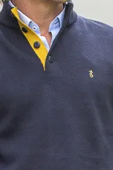 Buzo azul marino de algodón con cuello alto abotonado y detalles amarillos en el interior del cuello, puños y ruedo. Presenta mangas largas y logo bordado en el pecho.