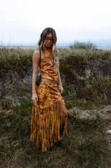 Pollera midi de cuero con estampado marmolado en tonos marrones y mostaza, de corte asimétrico con detalles de largos flecos colgantes en el borde inferior.