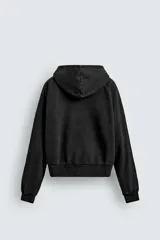 Sudadera con capucha y cierre frontal de cremallera, confeccionada en tejido de mezcla de algodón con interior afelpado. Presenta un diseño cropped, mangas largas, bolsillos frontales integrados en las costuras y acabados en rib. Posee un efecto lavado que le otorga una apariencia única.