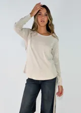 Remera de manga larga con cuello redondo, confeccionada en tejido de algodón ligero. Presenta un corte recto con ruedo ligeramente redondeado.