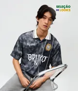 Remera de corte boxy confeccionada en tejido jacquard de poliéster con textura. Presenta cuello polo en color blanco con detalles en negro, mangas cortas y estampado frontal con lettering Bruxo y logo de Ronaldinho.