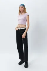 Top corto de manga corta, color negro con efecto desgastado o acid wash, cuello redondo y costuras verticales que definen la silueta.