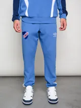 Pantalón deportivo azul claro con puños ajustados en los tobillos. Presenta el escudo del Club Nacional de Football bordado en la pierna izquierda y el logo de Umbro bordado en la derecha.