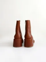 Bota de caña media color óxido, confeccionada en cuero, con plataforma y taco cuadrado texturizado, punta cuadrada y cierre lateral.