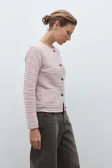 Chaqueta de punto color celeste, con cuello redondo, manga larga y cierre frontal con botones metálicos plateados.