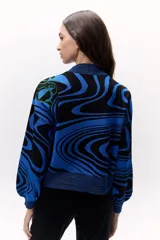 Sweater tejido de punto color azul con diseño marmoleado en negro y aplique bordado con contorno verde.