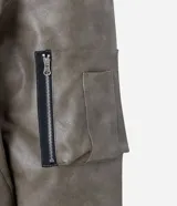 Campera bomber de poliuretano con acabado efecto cuero, cuello redondo, cierre frontal con cremallera, bolsillos delanteros y bolsillo utilitario en la manga. Presenta puños y ruedo elásticos, con forro interior en contraste.
