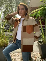 Camisa marrón con bloques de color beige y marrón oscuro. Presenta cuello camisero, cierre frontal con botones y un bolsillo de cuero en el pecho.