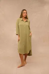 Vestido midi verde musgo estilo camisero, con cuello camisero, cierre frontal con botones y bolsillos laterales.