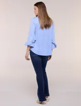 Blusa celeste con estampado de lunares blancos, cuello en V y mangas 3/4 terminadas en volados.