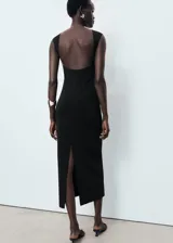 Vestido midi de corte recto y diseño minimalista, confeccionado en tejido elástico. Presenta cuello barco, tirantes anchos, espalda descubierta y una abertura posterior en el bajo.