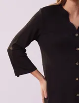 Blusa Ninety color beige con textura, cuello base con escote en V y abertura central con botones. Tiene un bolsillo en el pecho y mangas 3/4 regulables con presilla y botón.