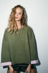 Jersey de punto de cuello redondo y manga larga con puños vueltos en contraste. Presenta un diseño holgado con aberturas laterales en el bajo.