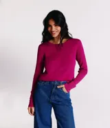 Suéter de punto color rosado, con cuello barco, mangas largas y puños con botones decorativos. El dobladillo también es acanalado.