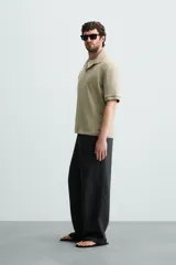 Polo de tejido canalé en color blanco, con cuello solapa y abertura frontal en V, de manga corta y corte regular.