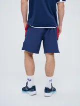 Bermuda deportiva Umbro del Club Nacional de Football, modelo Pro Training, de color azul marino con detalles blancos en el dobladillo. Presenta el escudo del club en una pierna y el logo de la marca en la otra.
