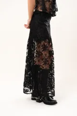 Pollera larga de encaje negro con silueta fluida y diseño asimétrico. Presenta un forro interno hasta la altura del frunce, dejando la parte inferior con transparencias que aportan movimiento.