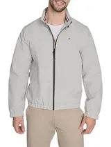 Campera tipo bomber de Tommy Hilfiger en color gris claro. Presenta cierre frontal completo, cuello mao con detalles internos distintivos de la marca, puños y ruedo elásticos, y el logo de la bandera bordado en el pecho.