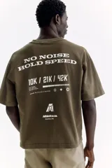 Remera de algodón verde militar con efecto lavado, cuello redondo de canalé, mangas cortas con hombros caídos y pequeño estampado tipográfico en el pecho.