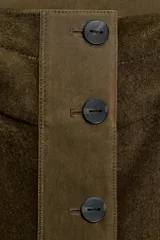 Parka oversize de corte recto confeccionada en tejido con mezcla de lana en color verde oliva. Presenta cuello alto con capucha, cierre frontal con botones y bolsillos laterales. Incluye detalles en tejido acolchado a contraste en la solapa frontal y puños.