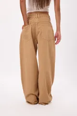 Jean de corte wide leg en color beige, con cintura de tiro medio y diseño de cinco bolsillos.