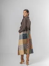 Falda midi de paño con estampa patchwork de inspiración escocesa, confeccionada en mezcla de lana. Presenta pinzas frontales, cintura elástica para mayor comodidad y un cinto desmontable a tono.