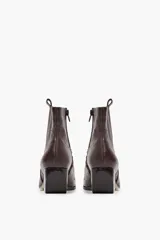 Bota corta de cuero vacuno color chocolate con textura tipo cocodrilo, diseño de estilo texano con costuras decorativas y taco cuadrado de madera.