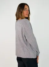 Sweater de punto con escote en V, manga larga y corte holgado. Presenta un diseño liso con costura central vertical en el frente y terminaciones acanaladas en puños y ruedo.