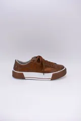 Zapatillas bajas color marrón con textura simil cuero de cocodrilo, cordones al tono y suela de goma blanca con detalle marrón.