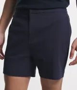 Bermuda de hombre, corte slim, color blanco con textura visible. Confeccionada principalmente en lino y algodón, con un pequeño porcentaje de elastano para mayor ajuste. Presenta cintura elástica y bolsillos laterales.