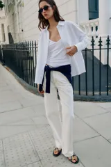 Camisa blanca de algodón con cuello solapa, manga larga y cierre frontal de botones.