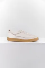 Zapatillas deportivas de cuero color blanco hueso con detalles bordados y suela color caramelo.