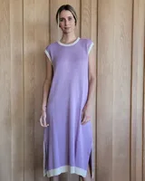 Vestido largo color lila, sin mangas, con cuello redondo y una gran estrella blanca estampada en la espalda. El cuello y el dobladillo inferior son de color beige.