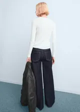 Pantalón de jean estilo wide leg de tiro alto, con diseño de cinco bolsillos, trabillas para cinturón y cierre frontal con cremallera y botón.