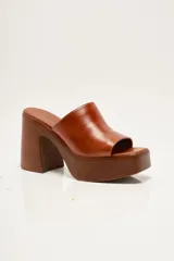 Zapato de plataforma tipo sueco, de empeine amplio en ante, con plataforma alta y taco ancho. Puntera cuadrada y diseño abierto en el talón.