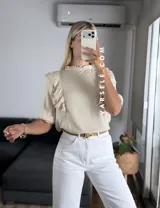 Blusa de símil lino color beige, con cuello redondo fruncido, doble volado en los hombros con detalle de encaje y manga 3/4.