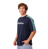 Remera Rusty modelo Zoren S27 de manga corta, color azul marino con diseño estilo bloque de color que incluye mangas y detalles en verde oscuro y una línea blanca en los hombros. Cuenta con el logotipo de la marca estampado en el pecho.