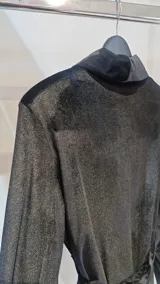 Blazer negro de terciopelo con hombreras, solapas cruzadas, bolsillos con solapa y lazo ajustable en la cintura.
