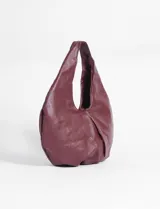 Cartera tipo hobo de gran tamaño, confeccionada en cuero sintético color bordó, con diseño holgado y asa integrada.