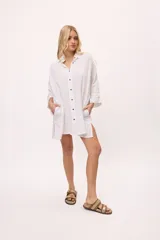 Vestido camisero blanco de algodón, con botones oscuros a contratono y detalles de zigzag en los puños y aberturas laterales.